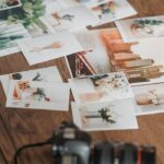 High angle many printed photos scattered on wooden table near professional photo camera in light room
